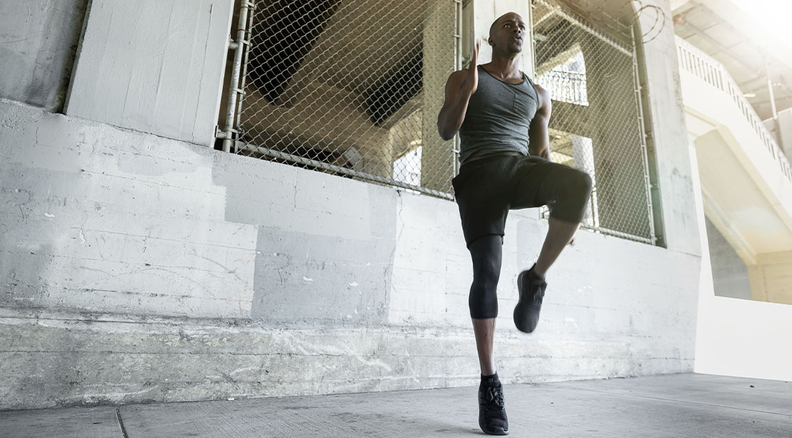 Fit man performing high knees for his Outdoor Strength and cardio workout